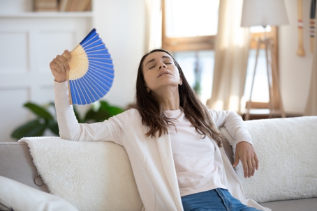 Woman using paper fan to alleviate heat.
