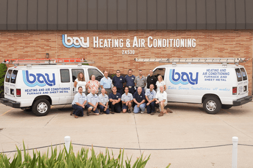 Bay Heating & Air Conditioning employees standing next to their vans. 